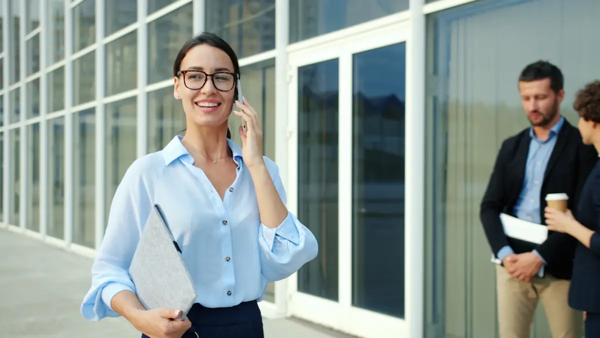 A lawyer on her phone outside a glass office building, a colleague behind her