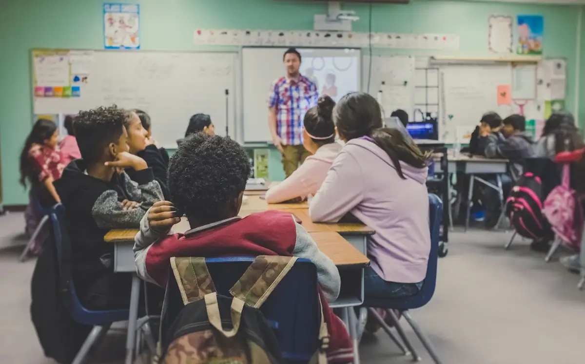 A teacher at the front of a class of learners at their desks