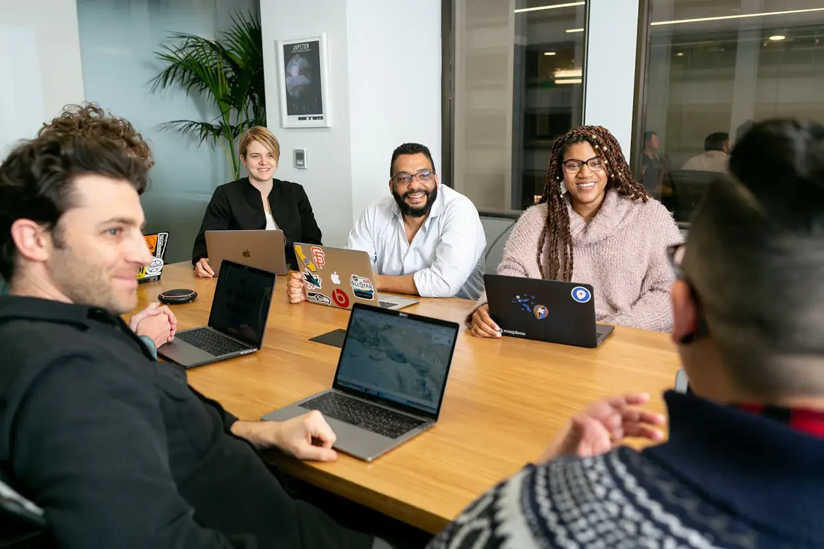 A team around a table of laptops in a bright meeting room