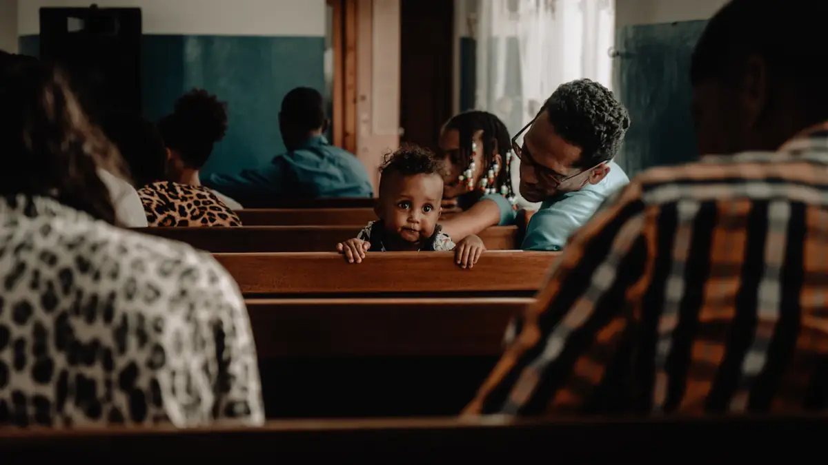 A family in a church pew, a toddler looking over the bench
