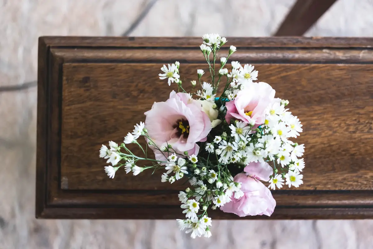 A small spray of pink and white flowers on a polished wooden coffin
