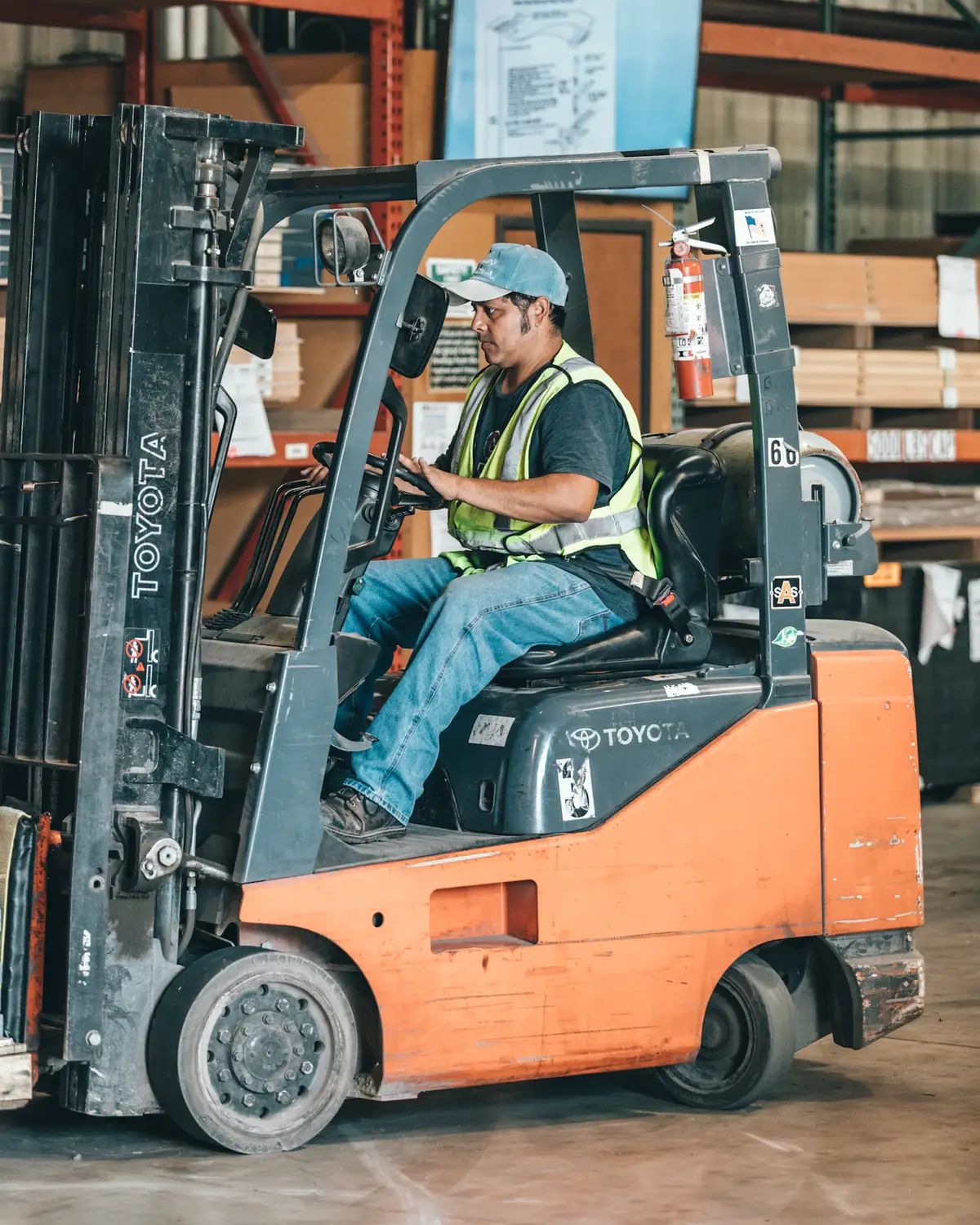 A forklift driver in a hi-vis vest in a stocked warehouse