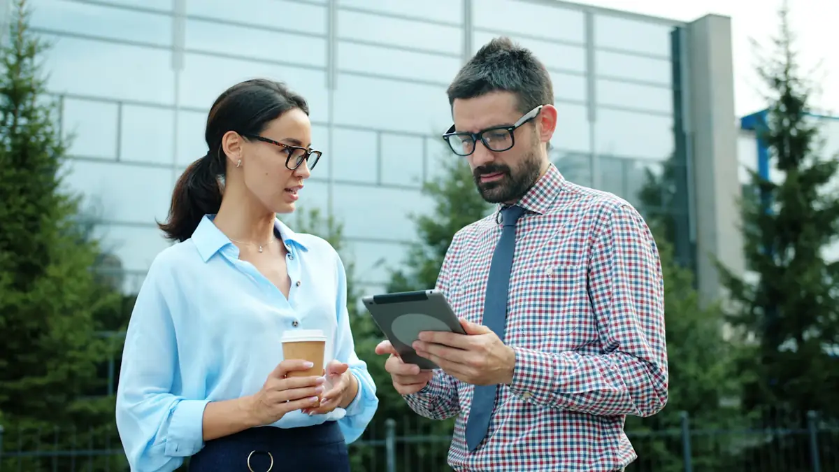 Two colleagues going over figures on a tablet outside their office