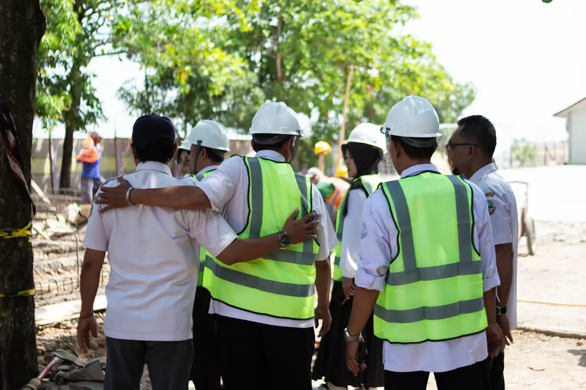 A site team in hard hats and hi-vis vests, arms round each other