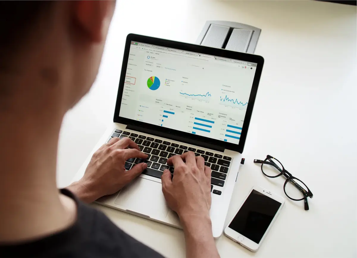 Hands on a laptop showing a dashboard of charts