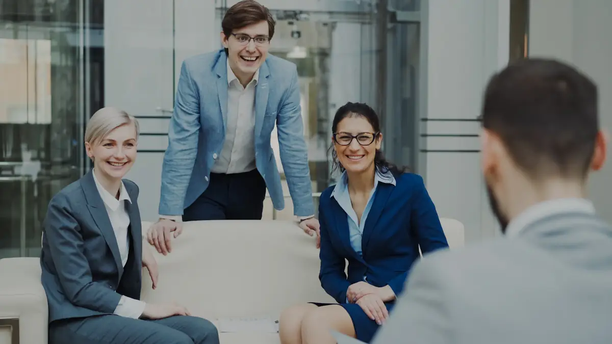 A team of colleagues in a meeting, smiling at a colleague across the table