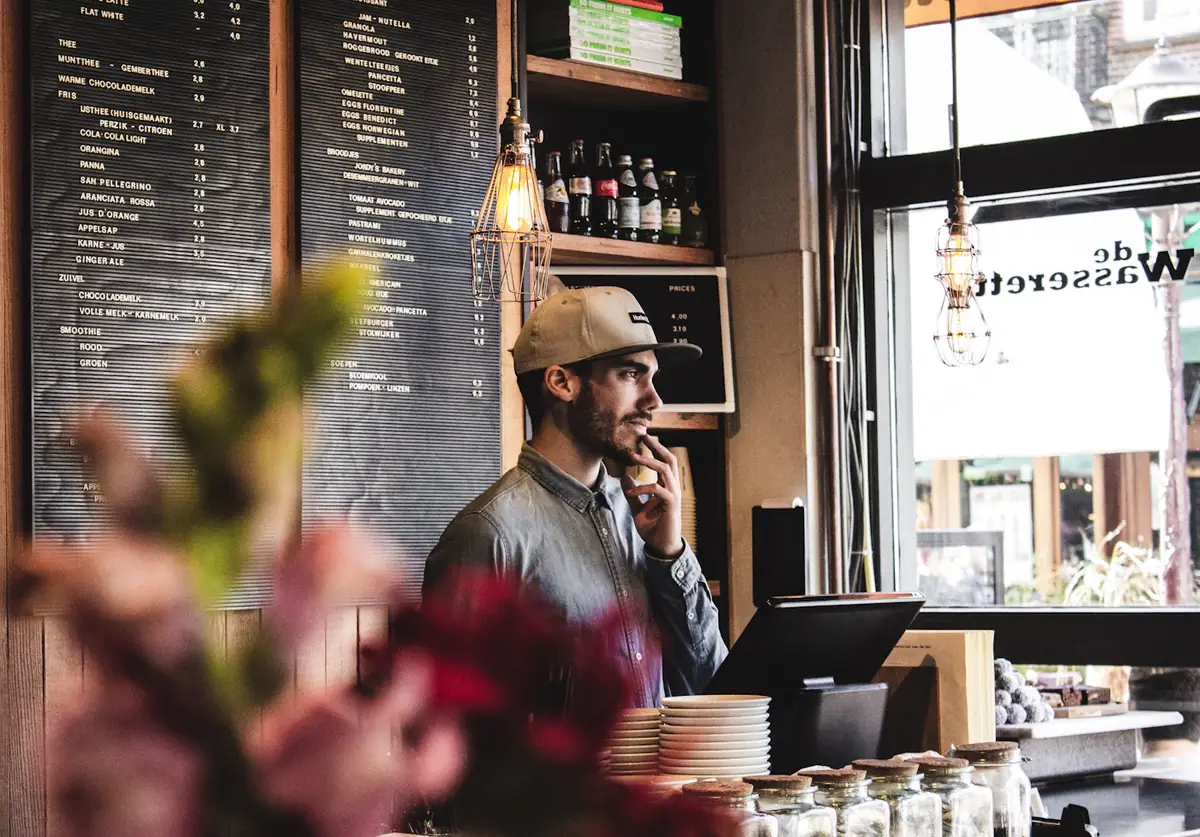 A café owner on the phone behind his counter