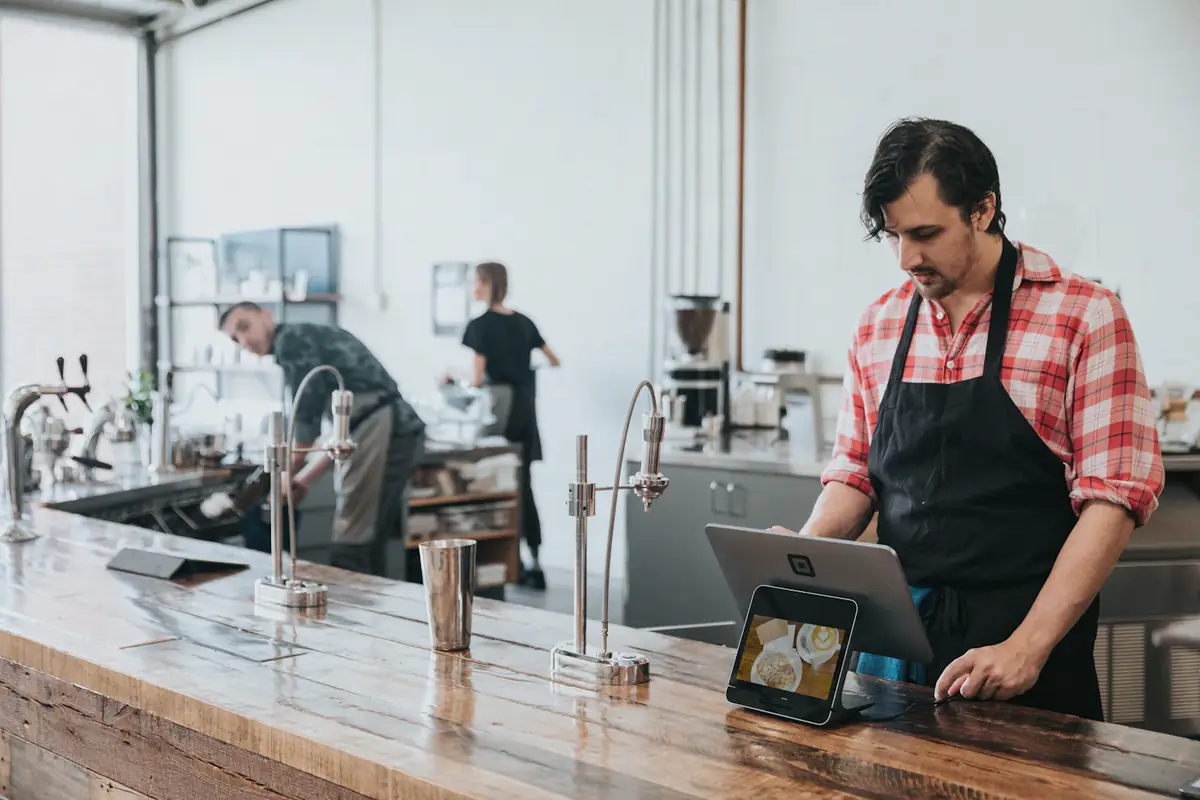 A café owner ringing up an order on a tablet till