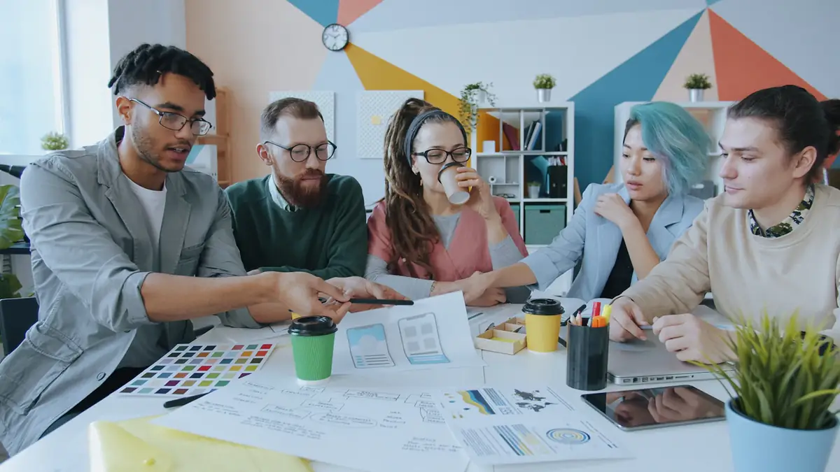 Designers around a table covered in sketches and colour swatches