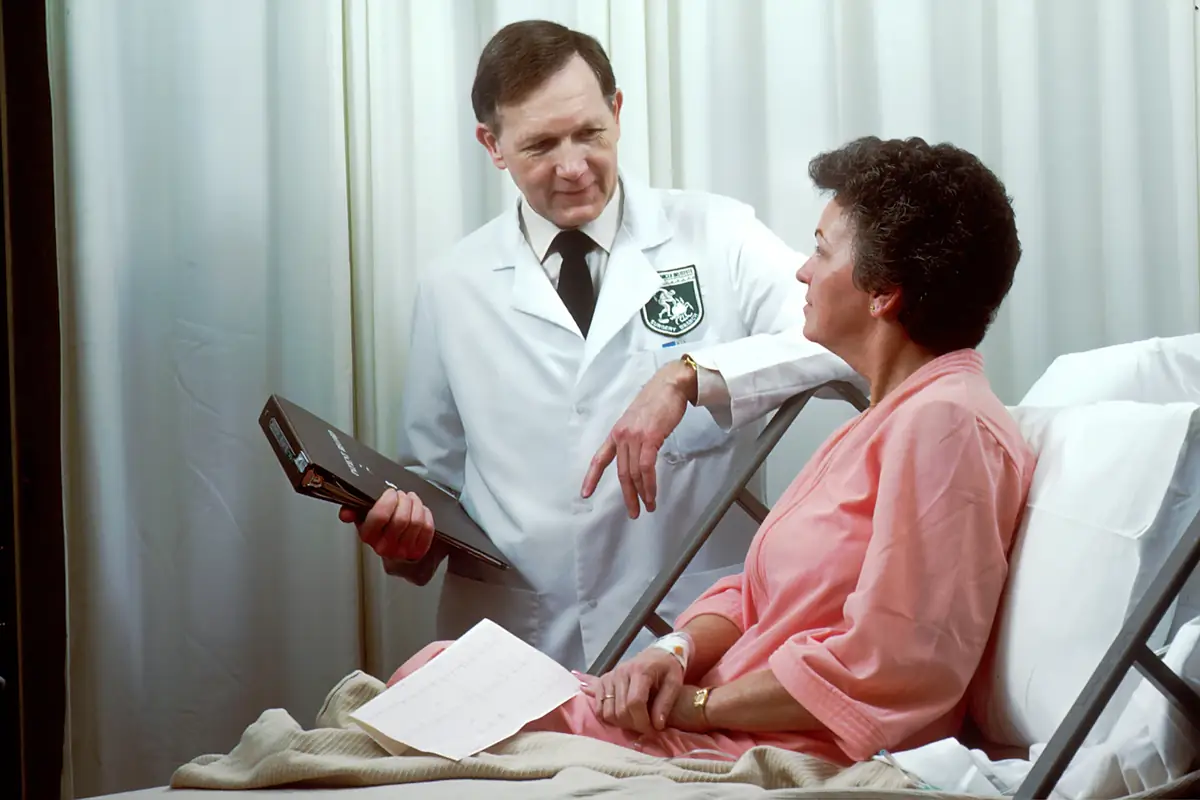 A doctor talking with a patient at her bedside
