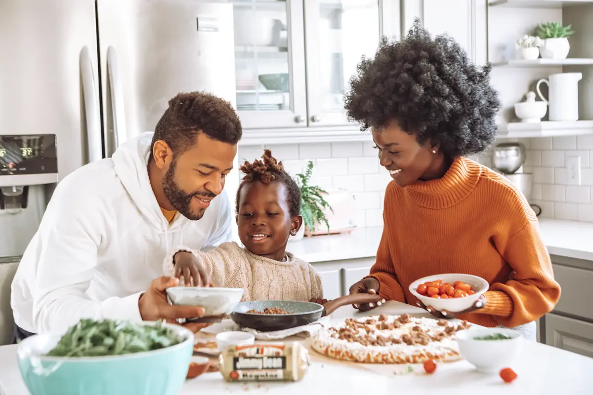 A couple cooking dinner with their young son in a bright kitchen