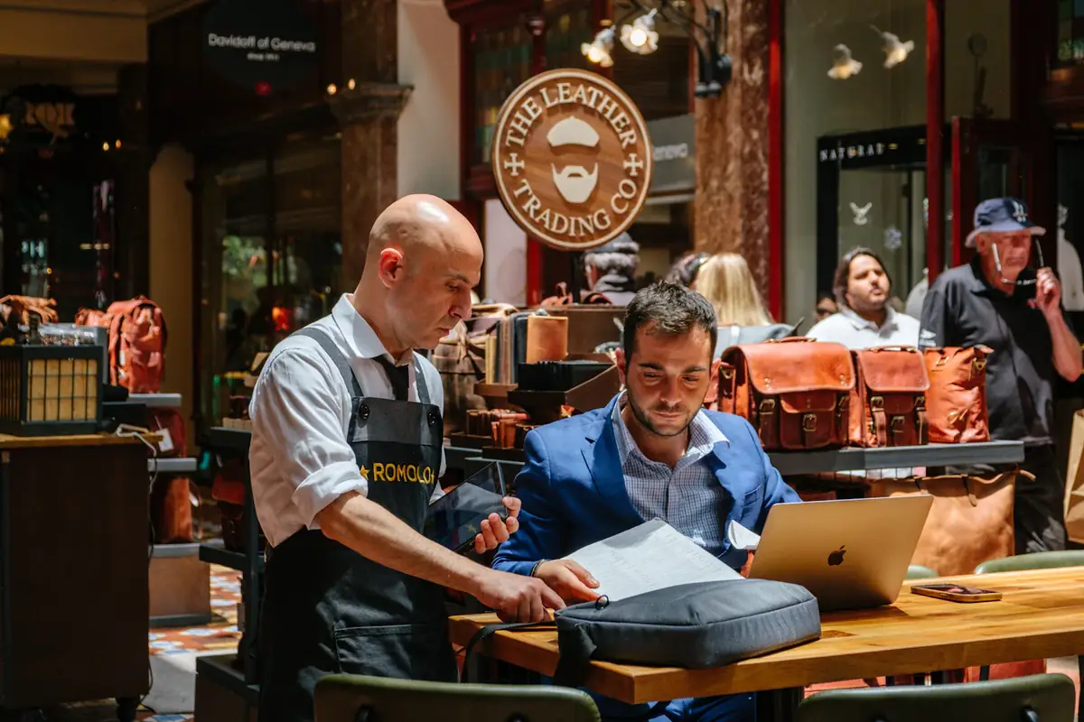 A shop owner helping a customer at a leather goods store