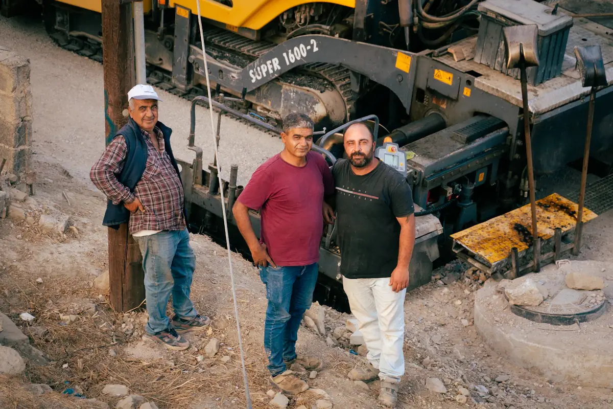 Three men on a construction site beside heavy machinery