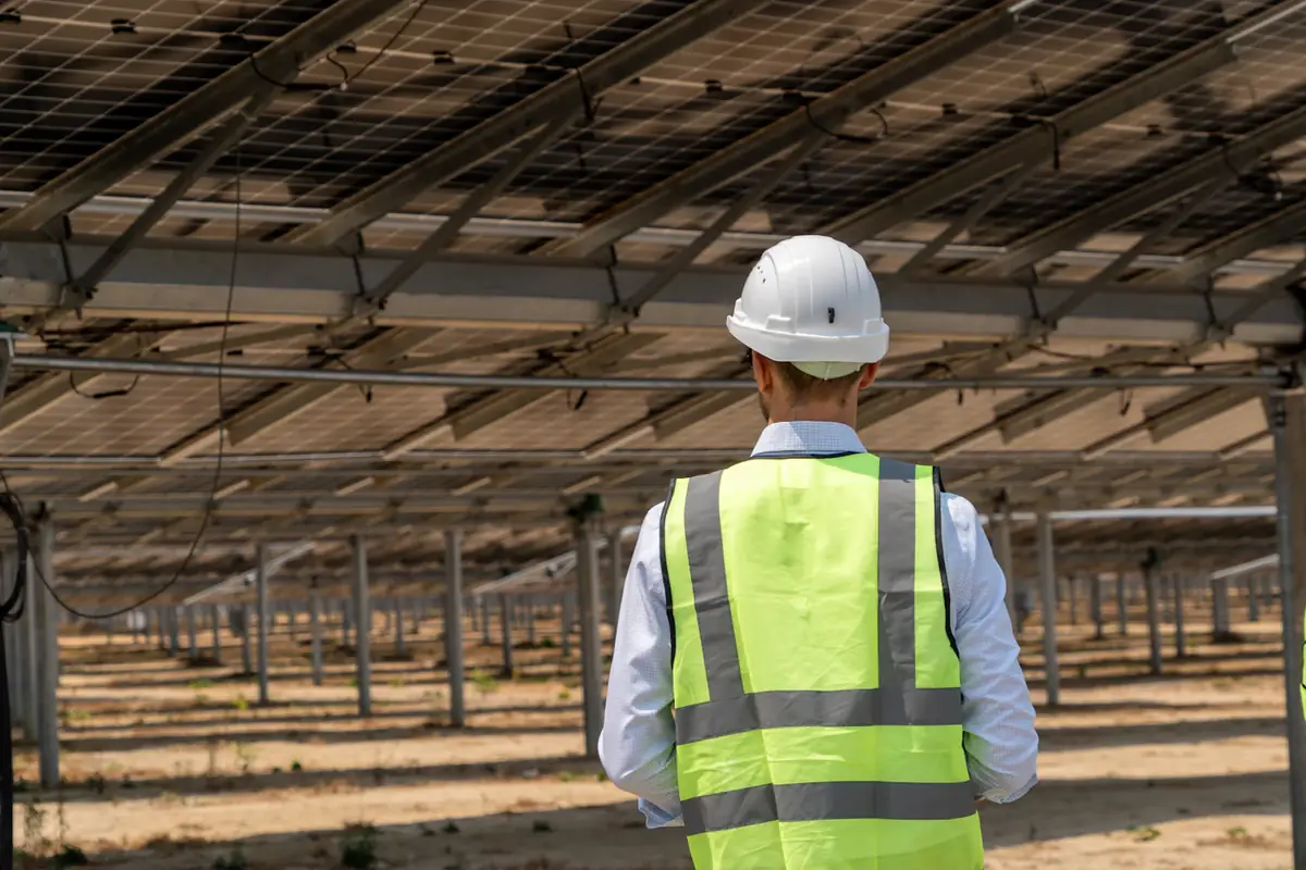 An engineer in a hard hat walking a solar farm