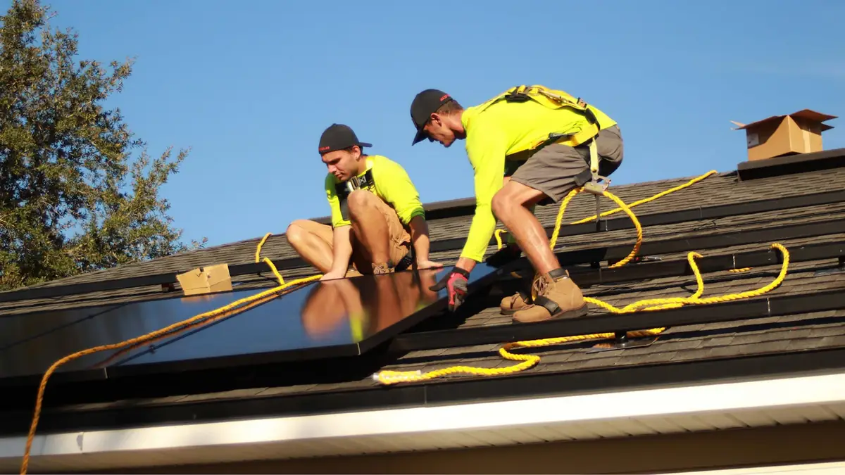 Two installers bolting panels to a roof