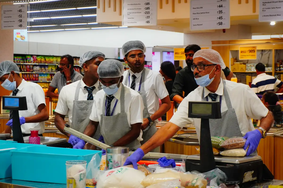 Supermarket staff weighing and packing at a busy counter