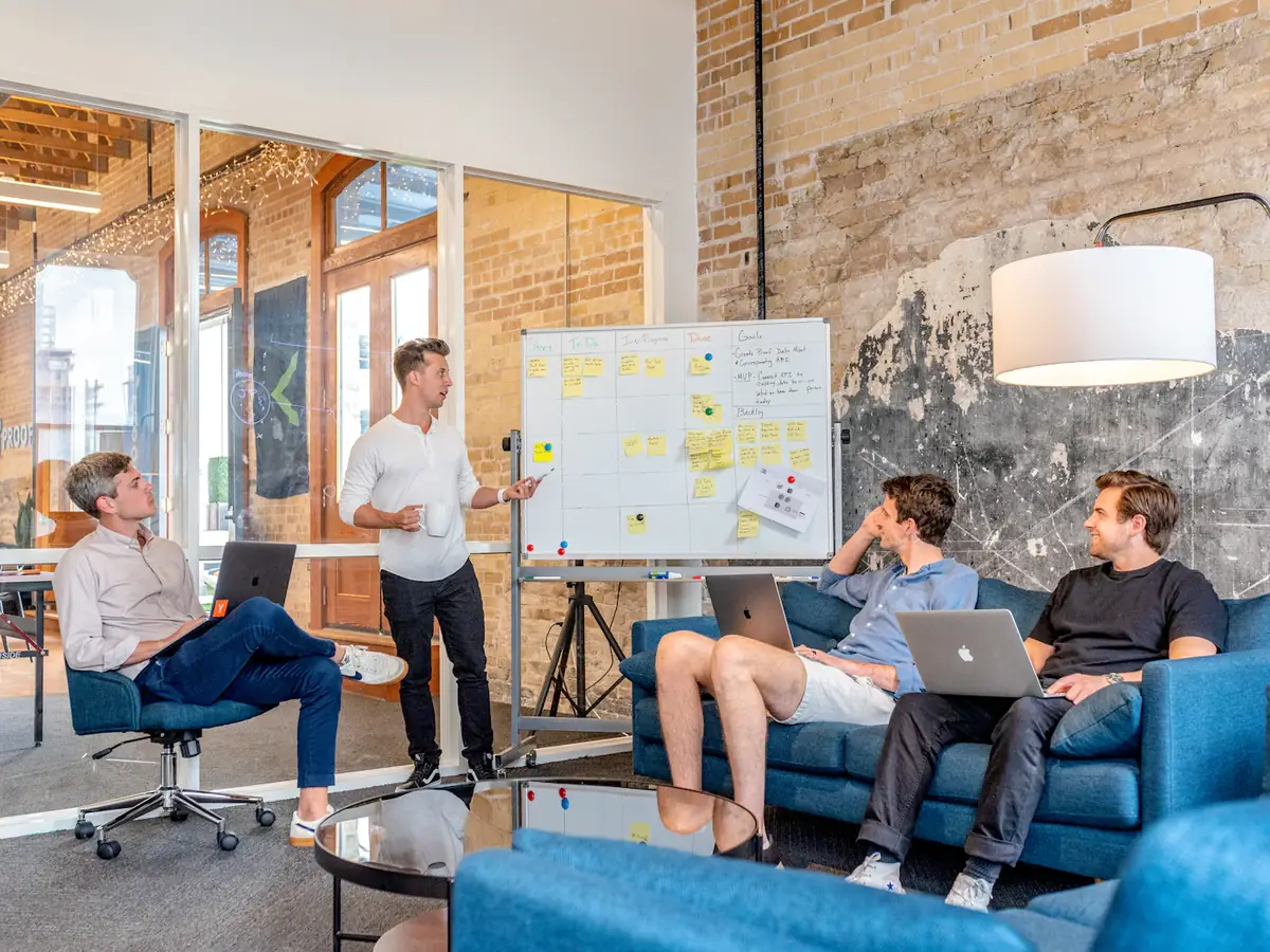 A product team on sofas and chairs around a whiteboard in a loft office
