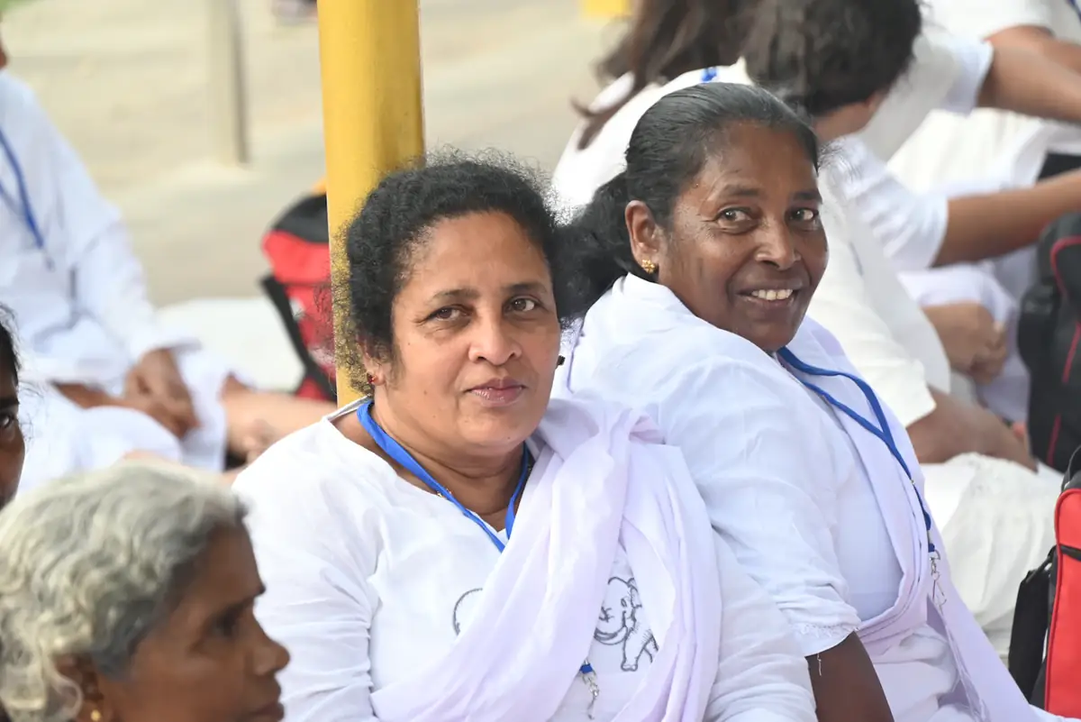 Two women volunteers in white smiling at an outreach day