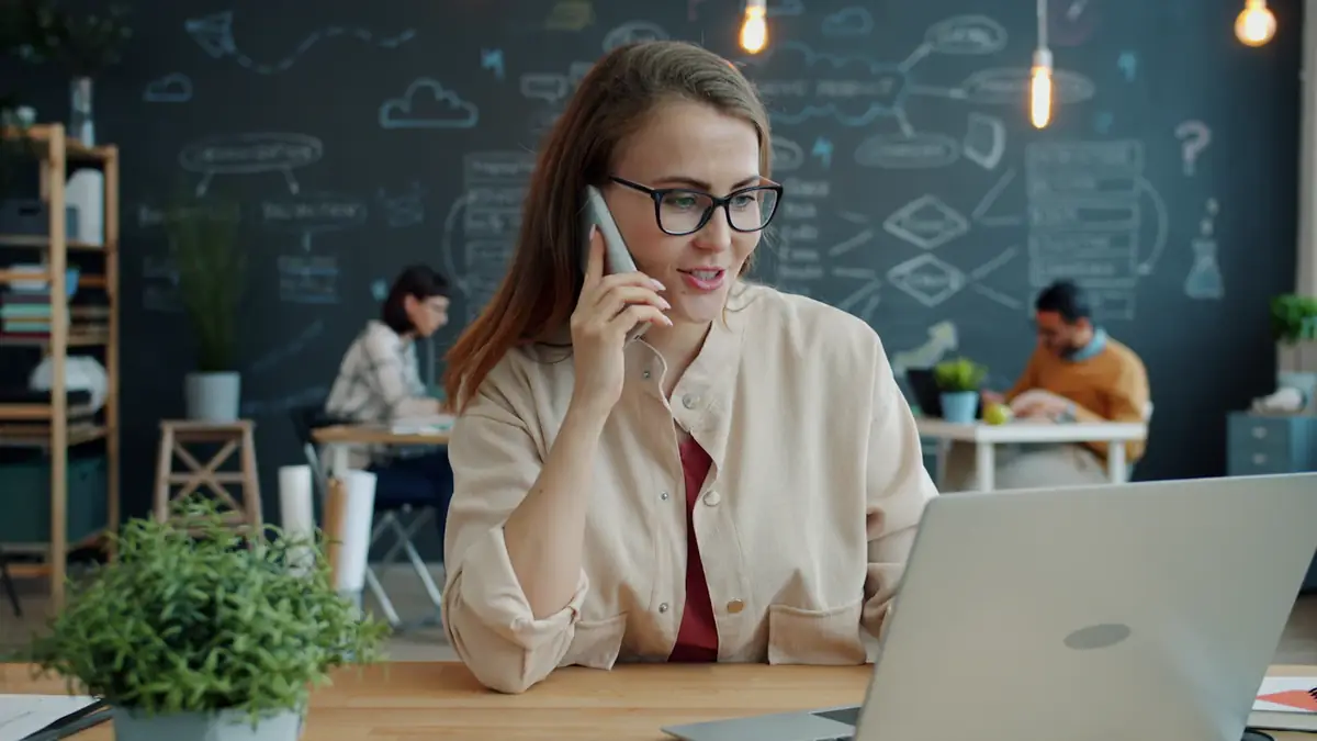 A woman on a call at her laptop in a bright office