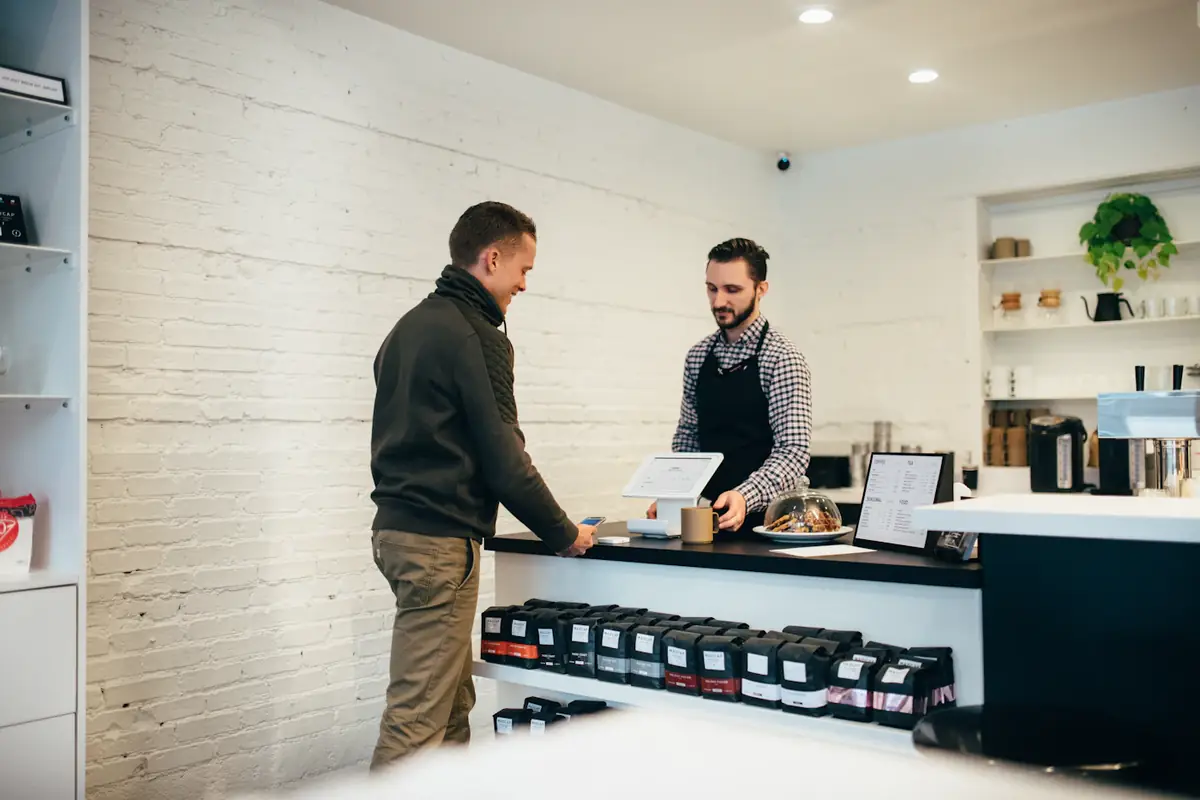 Two men talking across the counter of a small coffee roastery