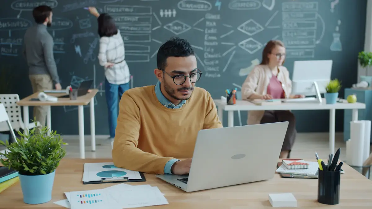 A man working at a laptop in a bright office